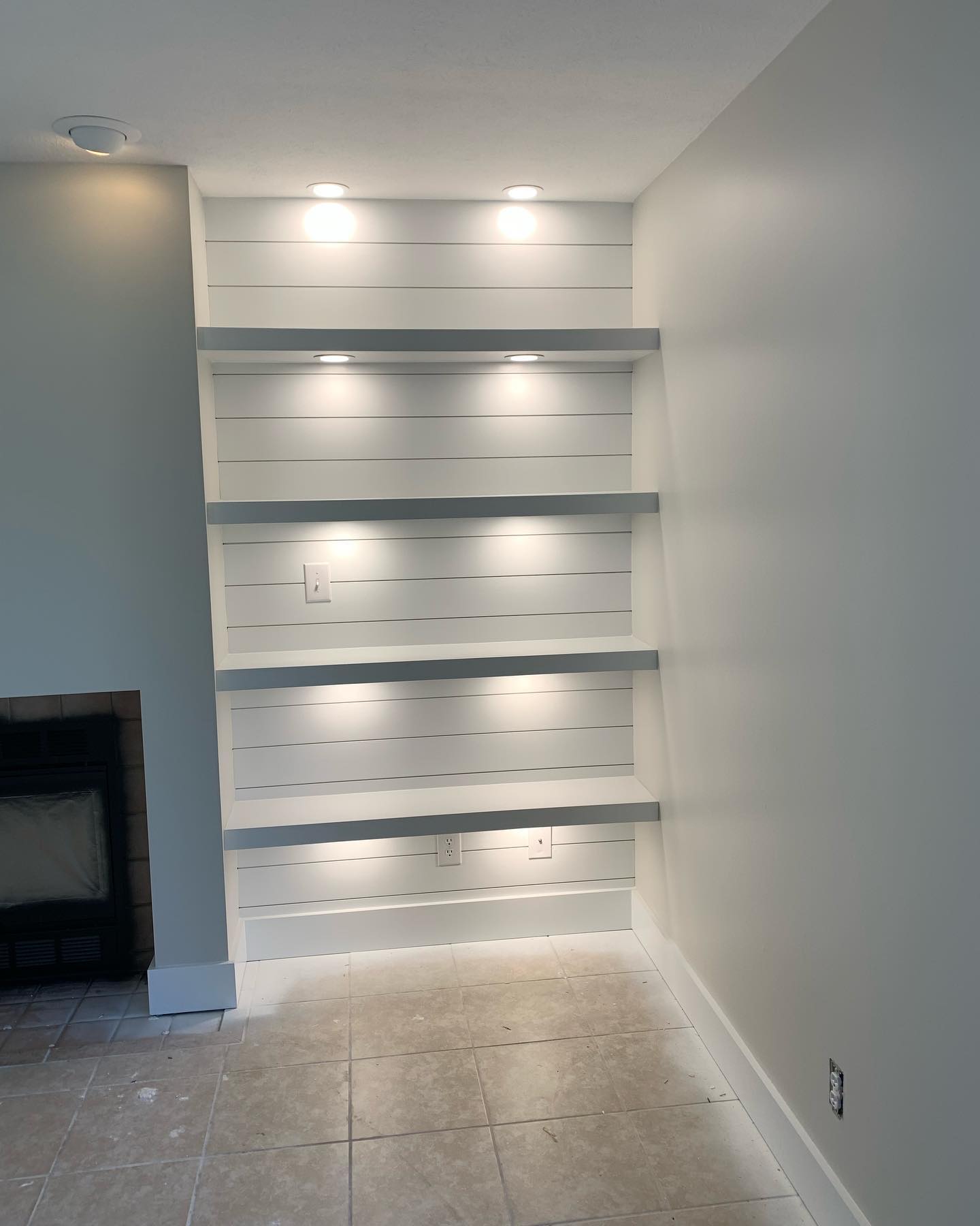 White shiplap built-in shelving with light-gray accent shelves and fireplace