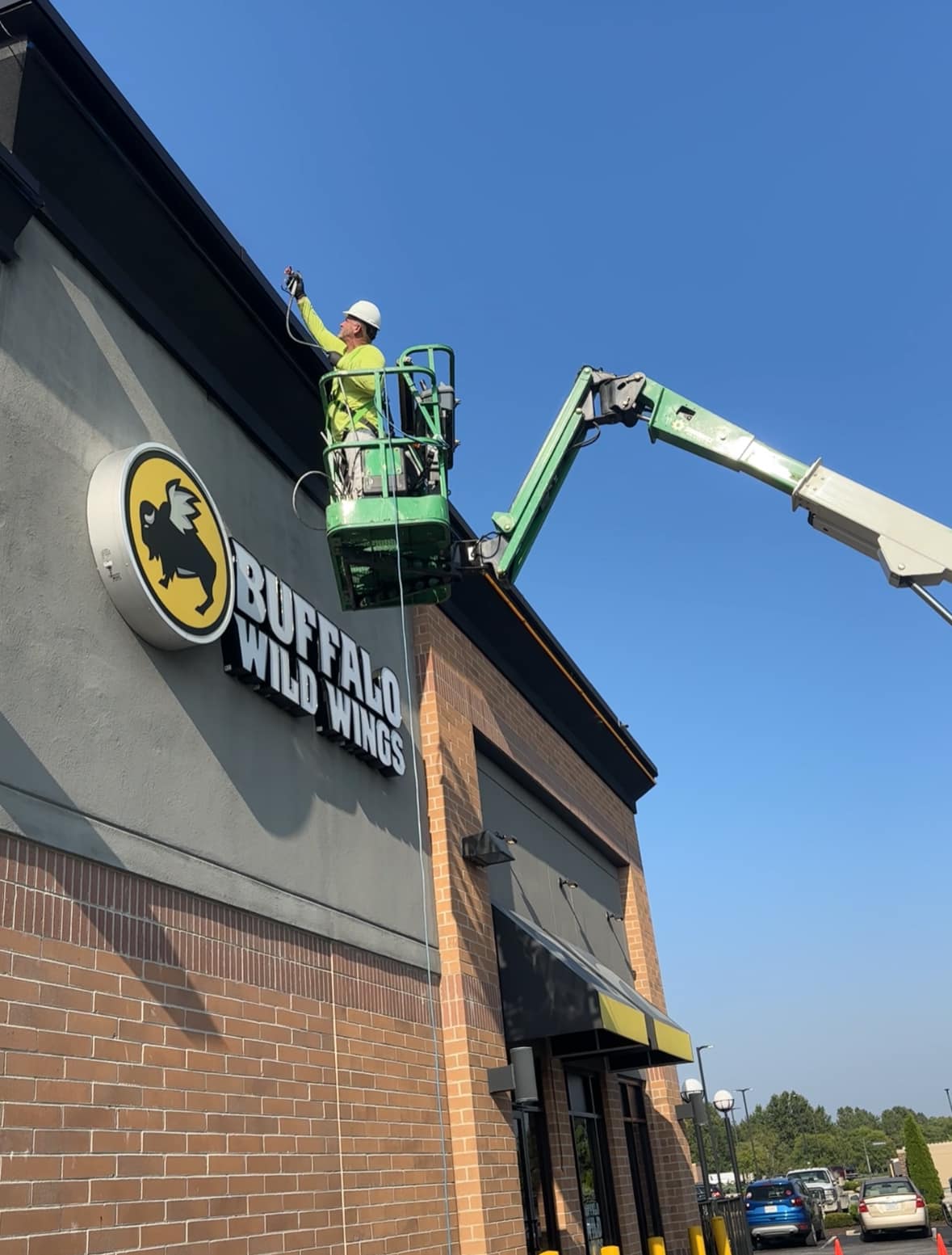 Painter on lift spraying Buffalo Wild Wings facade