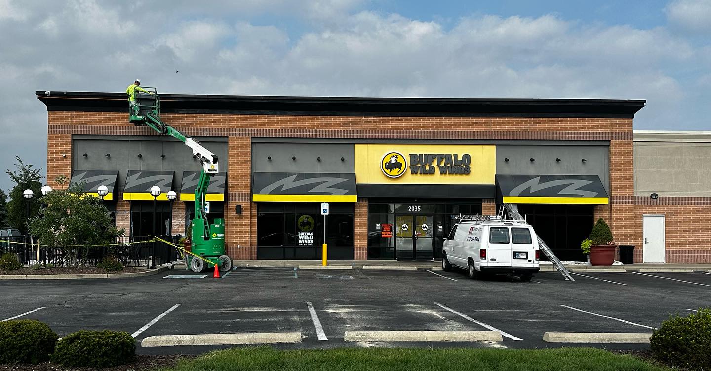 Buffalo Wild Wings storefront repaint, wide view with painter on lift