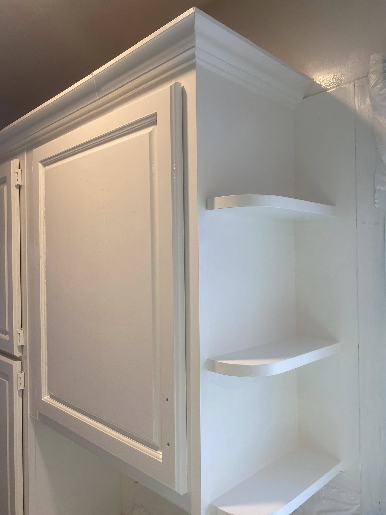 Close-up of white painted cabinet with curved corner shelving