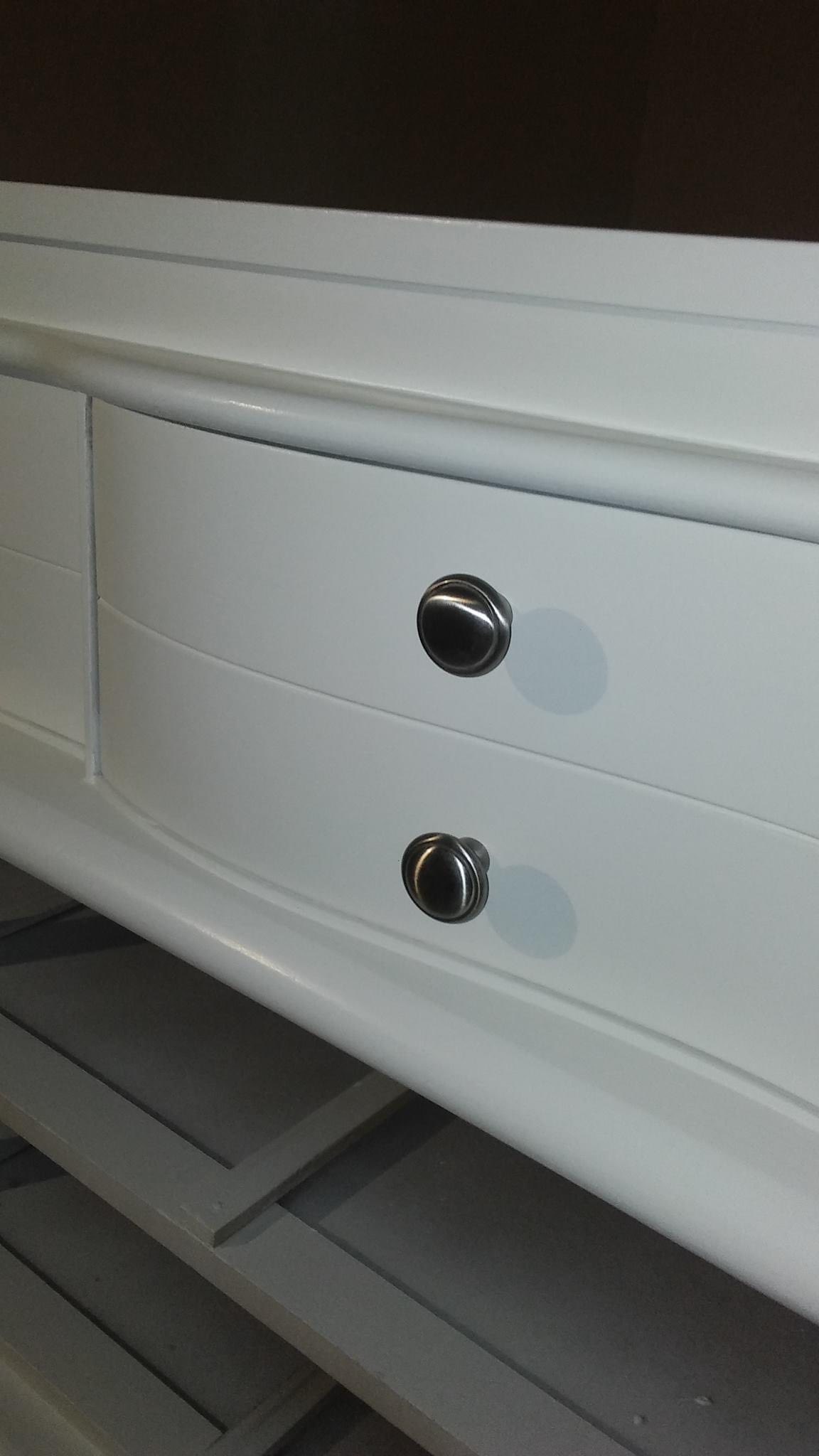 Close-up of refinished white dresser with curved drawer fronts and silver knobs
